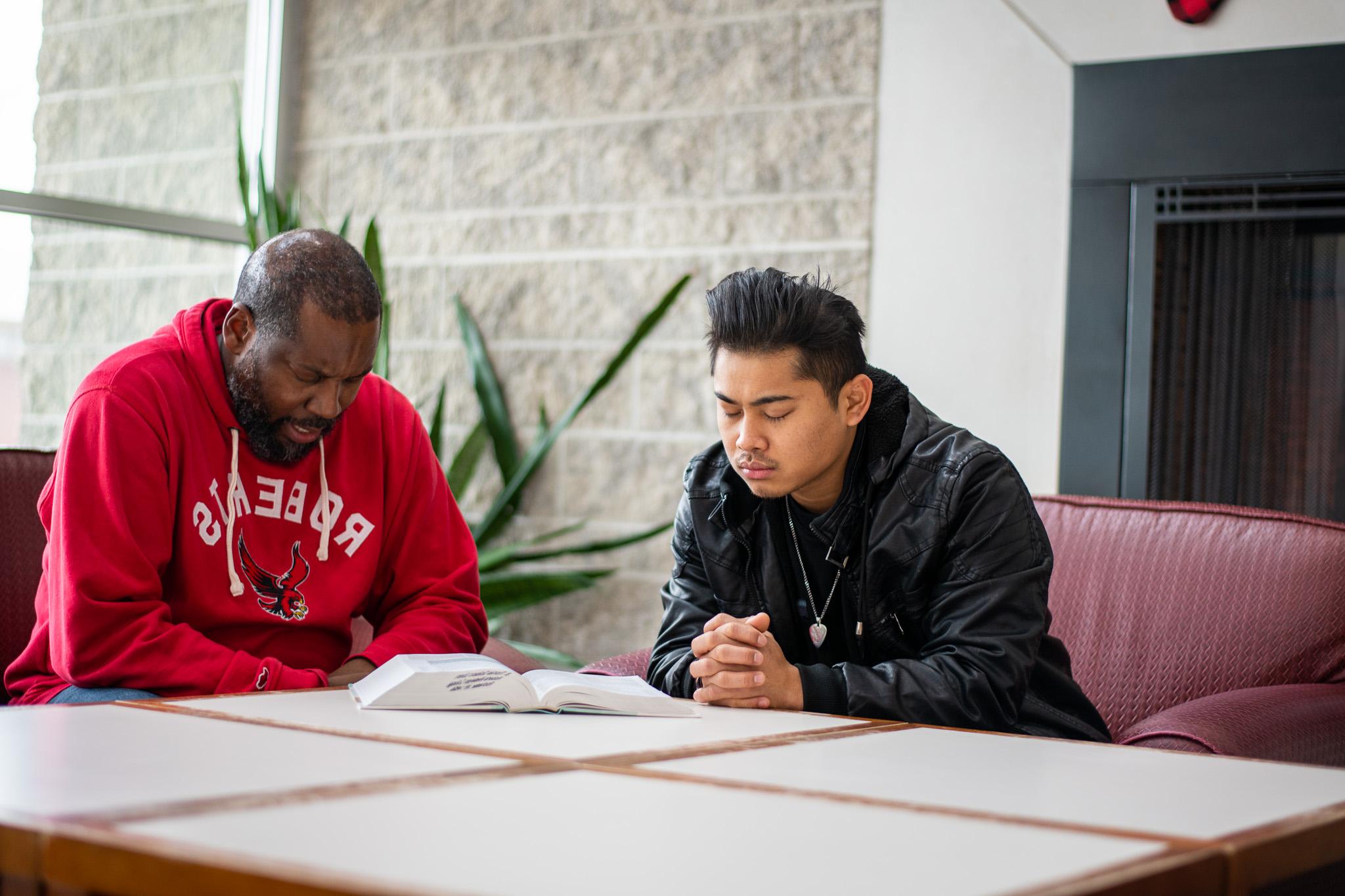 A Roberts Wesleyan University student and pastor pray together